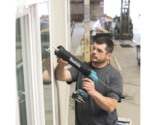 Un homme utilise un pistolet à cartouche sans fil Makita pour sceller une fenêtre.