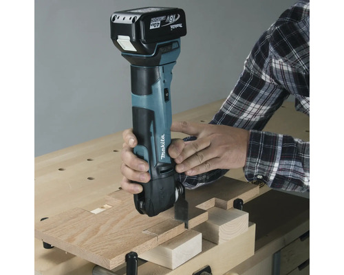 Outil multifonction sans fil Makita en cours d''utilisation pour couper du bois