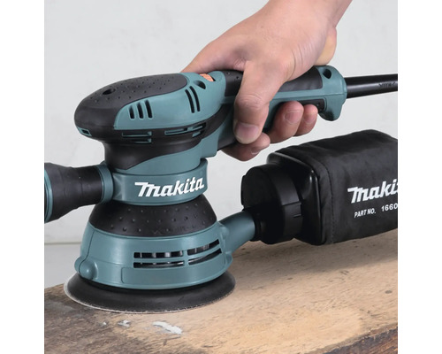 Ponceuse excentrique Makita en cours d''utilisation sur une surface en bois
