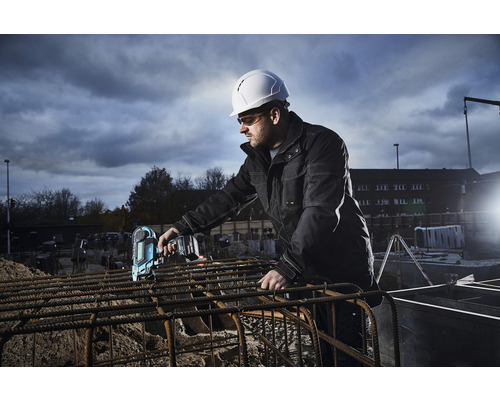 Un ouvrier du bâtiment portant un casque de protection utilise une attacheuse à batterie sur un chantier.