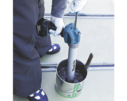 Artisan mélangeant du matériau avec un mélangeur Makita dans un seau.
