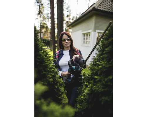 Femme coupant une haie avec un taille-haie dans le jardin.