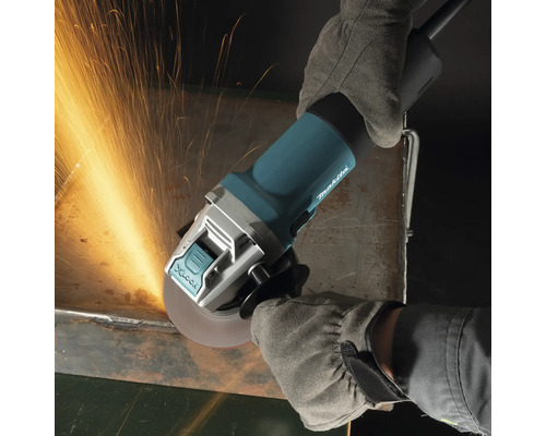Meuleuse d''angle Makita en fonctionnement avec des gants de protection, des étincelles jaillissent