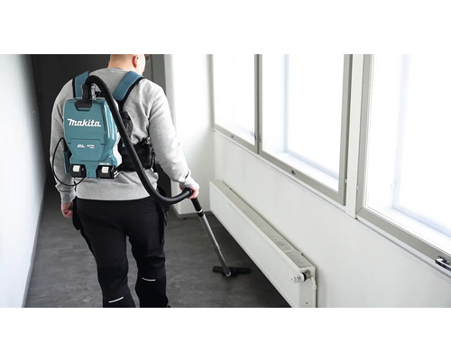 Eine Person benutzt einen Makita Rucksackstaubsauger in einem Gebäude.