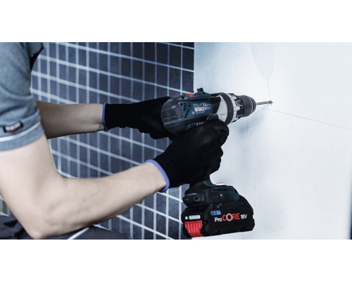 Ein Mann bohrt mit einer Bohrmaschine ein Loch in eine Wand.