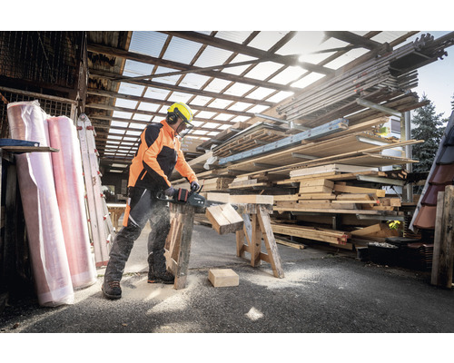 Homme sciant du bois avec une tronçonneuse à batterie à l''extérieur.