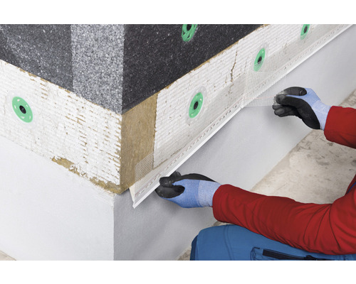 Gros plan d''une personne installant un système d''isolation de façade avec un tissu d''armature sur un mur de maison.
