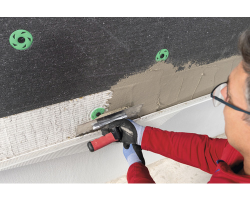 Handwerker trägt Putz auf Dämmplatte mit Dämmstoffdübel auf