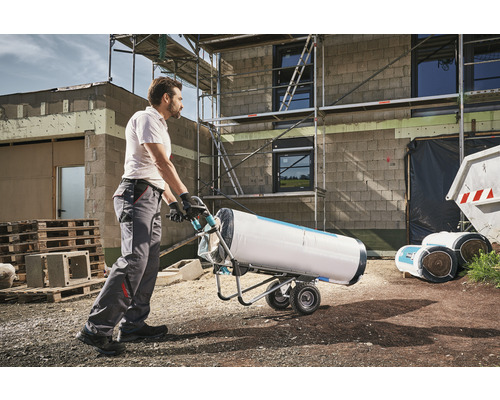 Un homme transporte un rouleau d''isolant avec un chariot de transport sur un chantier.
