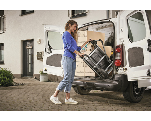 Une femme charge des cartons de déménagement dans une camionnette à l''aide d''un diable.