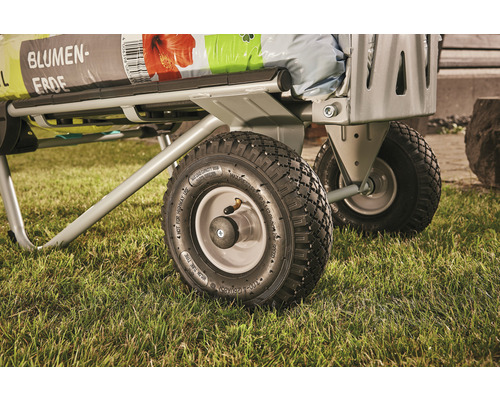 Vue détaillée d''un chariot de transport avec du terreau sur une pelouse.