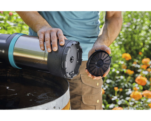 Mann setzt Filter in eine Regenfasspumpe ein.