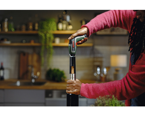 Szene einer Person, die mit einem elektrischen Korkenzieher eine Weinflasche öffnet. Bosch Logo.