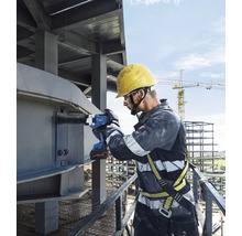 Ein Bauarbeiter benutzt einen Akku-Schlagschrauber an einer Stahlkonstruktion.