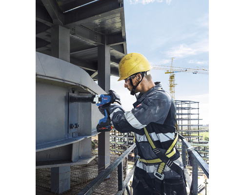 Ein Bauarbeiter benutzt einen Akku-Schlagschrauber an einer Stahlkonstruktion.