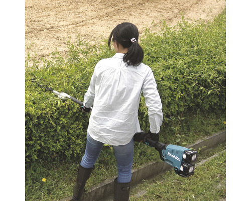 Eine Frau benutzt eine Akku-Heckenschere von Makita im Garten.