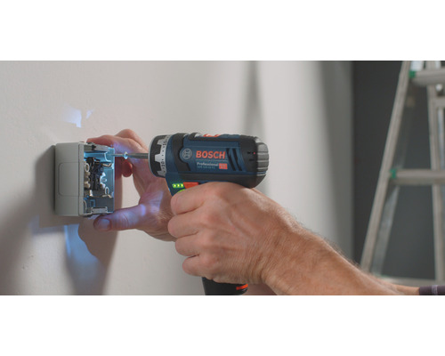 Électricien fixant une prise au mur avec une visseuse sans fil Bosch.