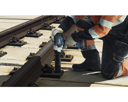 Un ouvrier fixe un rail de chemin de fer avec une clé à choc sans fil.