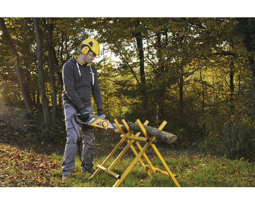Mann sägt Holzscheit mit elektrischer Kettensäge auf einem Sägebock