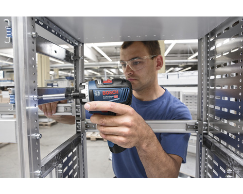 Ein Mann befestigt mit einem Akku-Bohrschrauber eine Metallschiene.