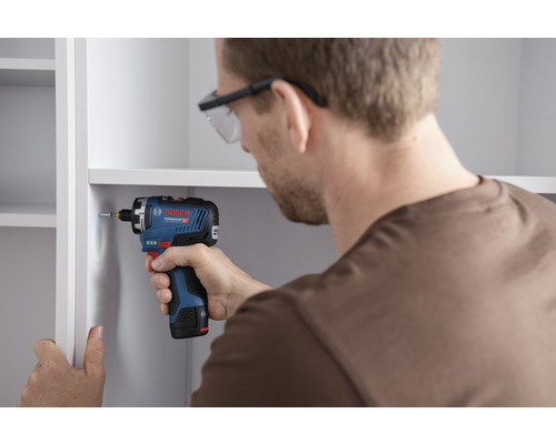 Mann schraubt mit einem Akku-Bohrschrauber ein Regal zusammen