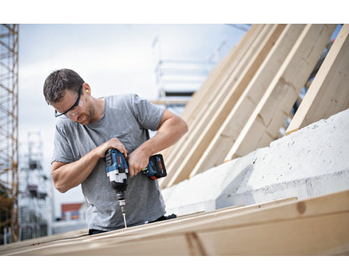 Un artisan fixe des vis à un cadre en bois à l''aide d''une visseuse sans fil.