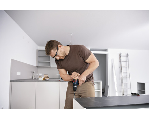 Ein Mann arbeitet mit einem Akku-Bohrschrauber in einer Küche.