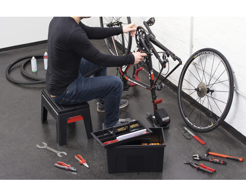 Eine Person repariert ein Fahrrad mit Werkzeug aus einem Werkzeugkasten