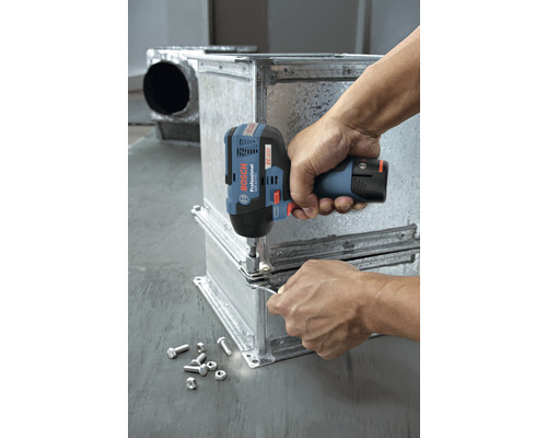 Une personne fixe des pièces métalliques à l''aide d''une clé à chocs sans fil. Des vis et des écrous sont posés à côté.