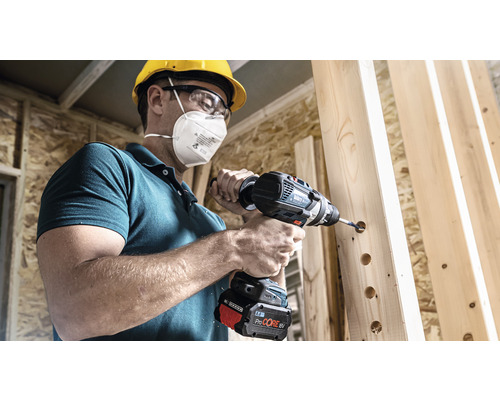 Ein Mann bohrt mit einem Akku-Bohrschrauber Löcher in Holz.