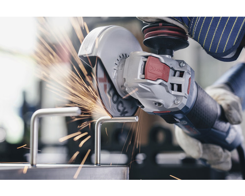 Une personne utilise une meuleuse d''angle pour couper une pièce de métal, produisant des étincelles.