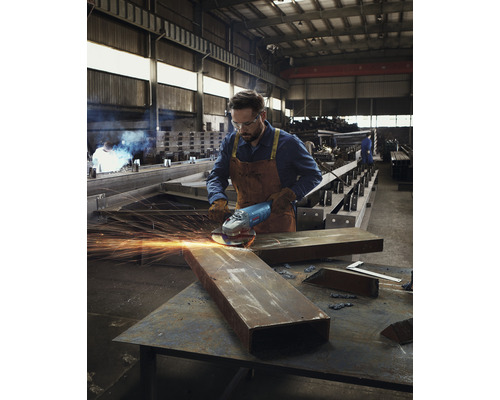 Un homme meule du métal avec une meuleuse d''angle dans un atelier.