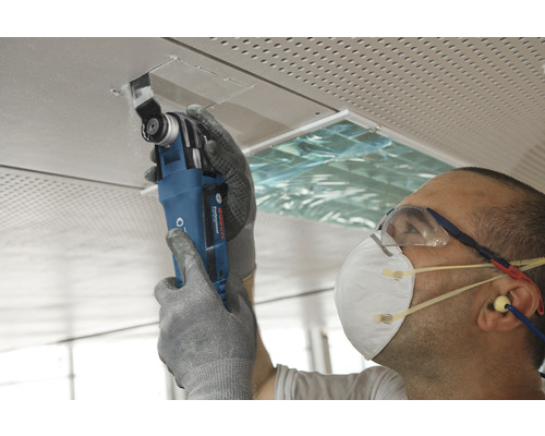 Artisan travaillant avec un outil multifonctionnel sur un panneau de plafond