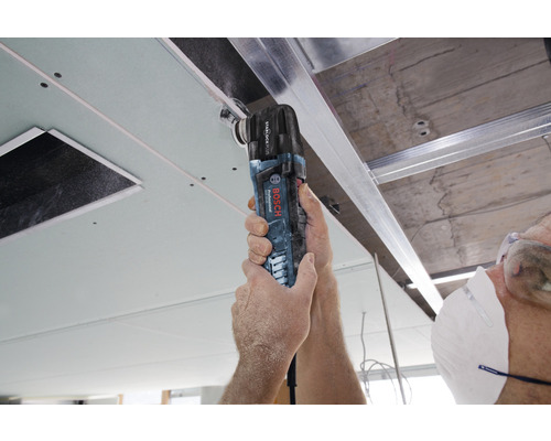 Un artisan utilise un outil multifonction de Bosch Professional pour travailler une plaque de plafond.