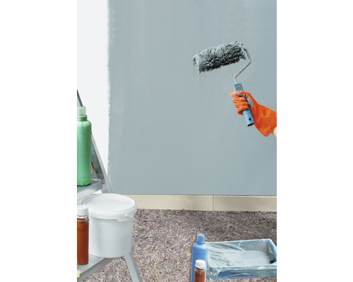 Wand streichen mit Farbroller, Farbeimer und Abdeckmaterial auf dem Boden.