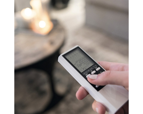 Hand hält eine Fernbedienung für ein elektrisches Gerät.