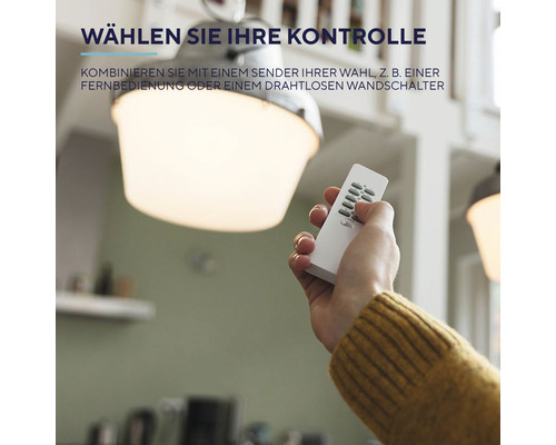 Hand mit Fernbedienung unter einer Deckenleuchte