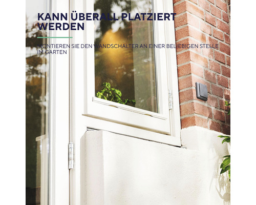 Ausschnitt eines Hauses mit Fenster und einem montierten Wandschalter.