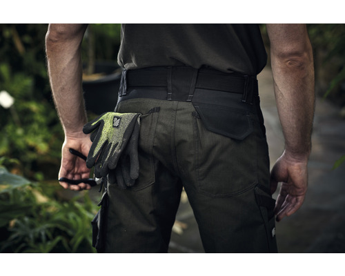 Une personne porte un pantalon de travail avec des gants de travail dans la poche arrière.