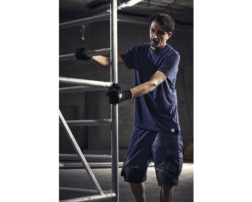 Un homme en vêtements de travail assemble un échafaudage.