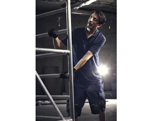 Un homme en vêtements de travail tient un échafaudage.