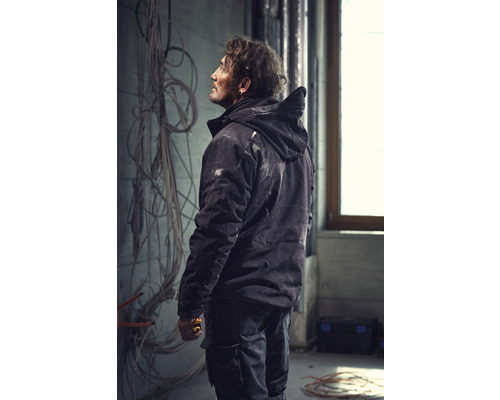 Artisan en vêtements de travail travaillant dans une pièce avec des câbles apparents