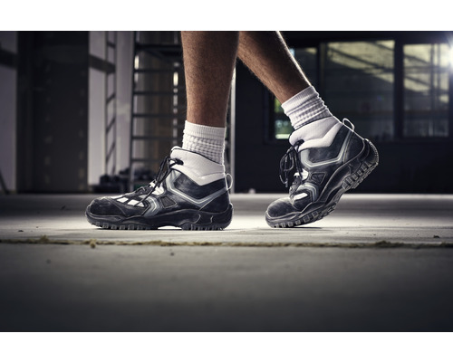 Une paire de chaussures de travail noires à lacets sur un sol en béton