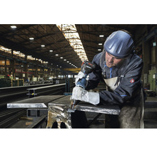 Metallarbeiter mit Akku-Blechknabber im Werkstattbereich beim Bearbeiten von Metall
