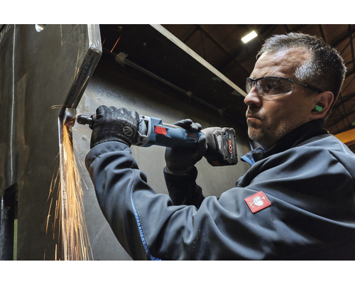 Ein Mann verwendet einen Akku-Geradschleifer an einem Metallwerkstück, wobei Funken entstehen.