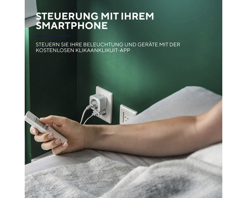 Person im Bett, die eine smarte Steckdose mit einer Fernbedienung steuert