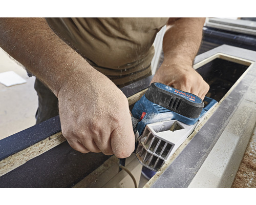 Handwerker hobelt Holz mit einem Elektrohobel der Marke Bosch