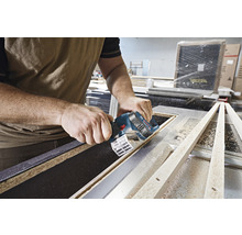 Une personne utilise une scie plongeante sans fil Bosch pour couper une pièce de bois.