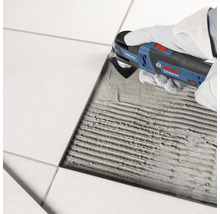 Coupe-carreaux en cours d''utilisation pour retirer le coulis entre les carreaux.
