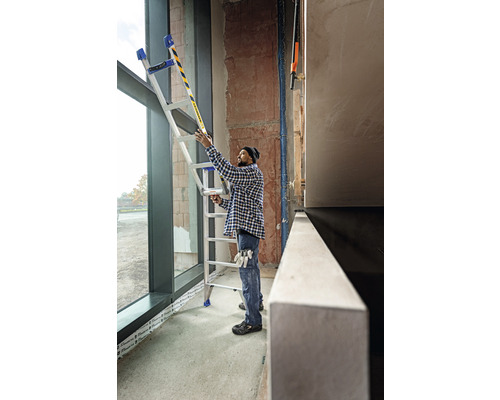 Eine Person benutzt eine Mehrzweckleiter an einem Fenster auf einer Baustelle.